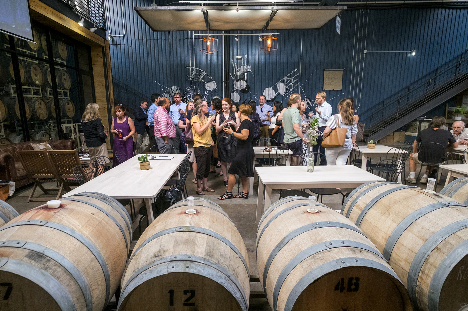 People drinking wine with casks in the foreground